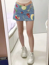 Person wearing a colorful checkered skirt with fruit patterns and white sneakers in a room.